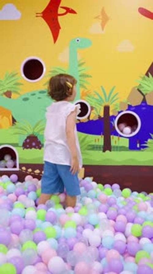 Girl Plays in Ball Pit with Dinosaur Theme