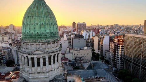 Aerial dolly in flying near green bronze dome of Argentine Congress building surrounded by Buenos Ai