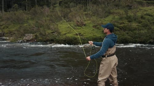Adult Fly Fishing in River Surrounded By Nature