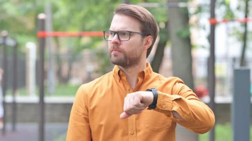 Man Checks Smartwatch in Urban Park Setting