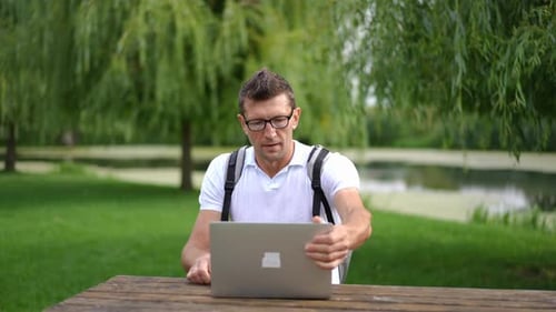 Freelancer satisfeito abrindo laptop e olhando em volta para começar a trabalhar no Spring Summer Park