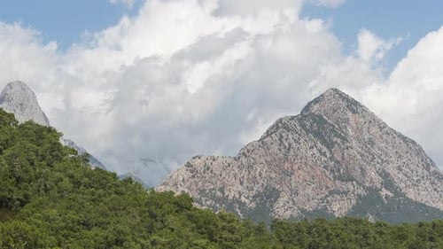 Majestic Mountains Covered in Green Trees and Clouds