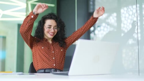 Happy Woman Relaxing at Office Desk With Laptop