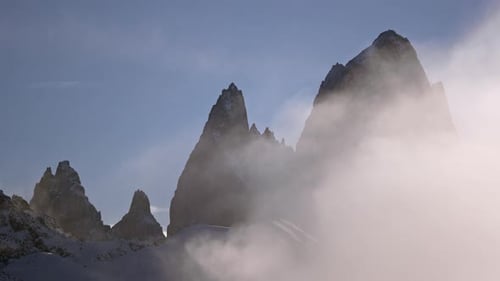Schroffe Berggipfel erheben sich über den Wolken in einer ruhigen, nebligen Landschaft