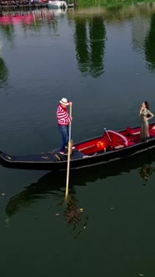 Gondolier riding a boat with a woman. Beautiful lady travelling in gondola along the river at sunset