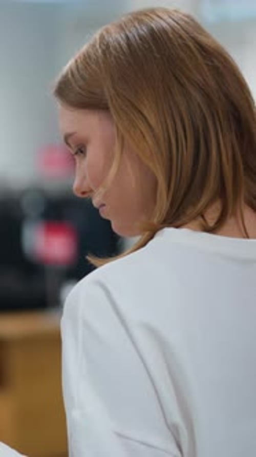 Woman Browsing and Touching Clothes in Retail Store with Mannequins in Background
