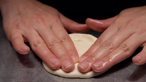Hands Flattening Dough on Metal Counter for Cooking
