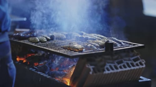 Eine Person nimmt gebratenen Fisch aus dem Grill