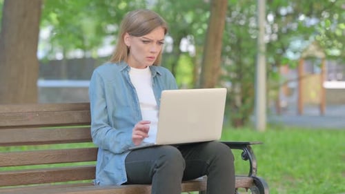 Woman Works on Laptop in Park, Looks Confused