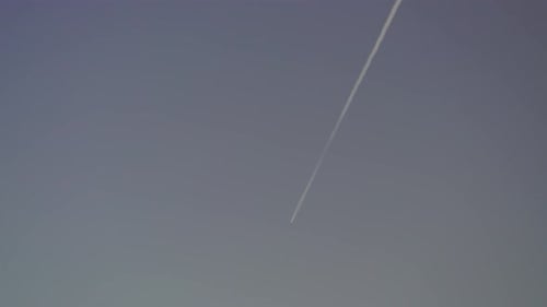 Airplane Flying Through Blue Sky with Trail