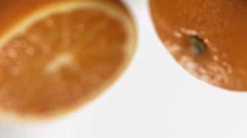 Makroaufnahme von Wassertropfen, die im Spiegel auf eine Orange fallen, in Superzeitlupe