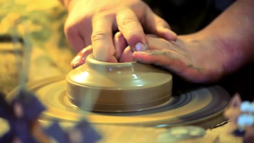 Master potter shaping clay dishes on a traditional wheel in a workshop