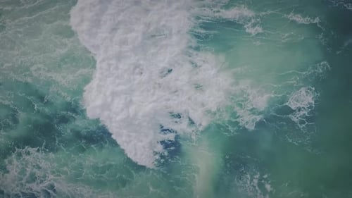 An aerial view of gentle waves rolling across the ocean surface, offering a peaceful and