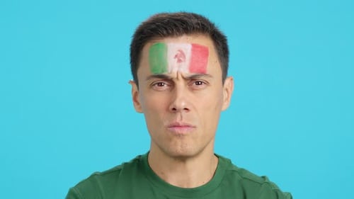 Hombre serio con una bandera mexicana pintada en la cara