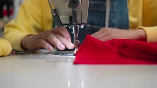 Seamstress Using Sewing Machine to Sew Red Fabric