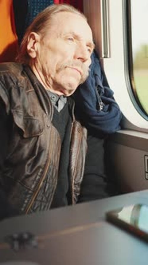 Pensive senior rides on train and looks out the window, Slow motion