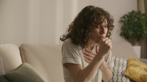Woman with Cough Sitting on Couch Indoors During Day