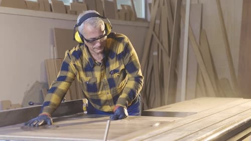 The carpenter is cutting wood in the workshop, working.