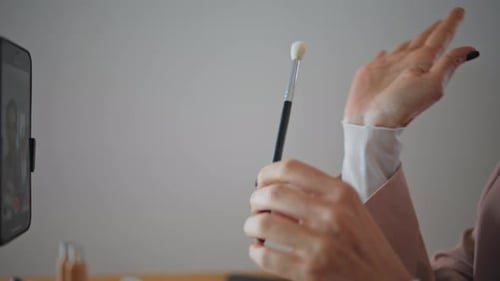 Blogger muestra con la mano el pincel a la cámara del teléfono inteligente en un primer plano de un apartamento. Mujer desconocida