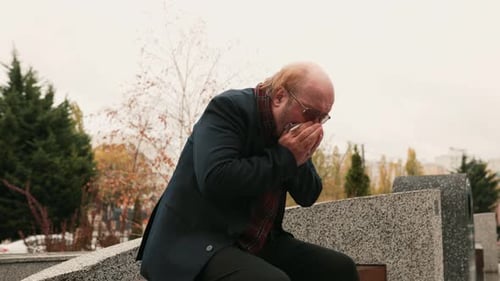 Senior Man Sitting on Bench Blowing Nose