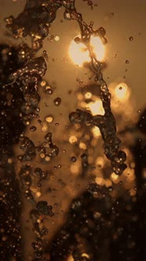 Golden Water Droplets Flowing in the Sunlight