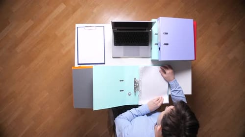 Man working with laptop and files, top view