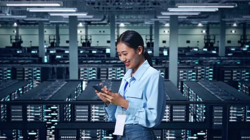 Side View Of Asian Business Woman Using Mobile Phone In Data Center