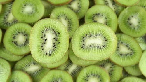 Half Of A Juicy Kiwi On A Background Of Rotating Kiwi Slices.