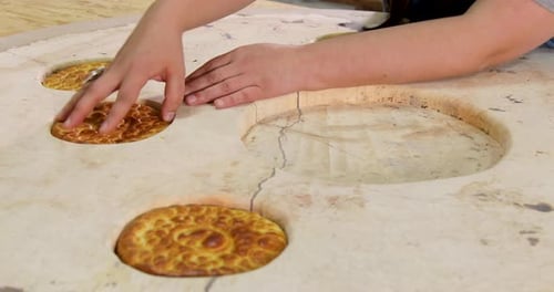 Hands Placing Breads into Round Surface Cavities