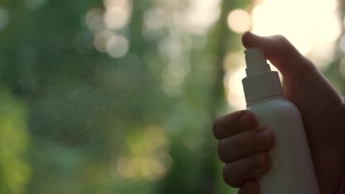 Hand Sprays Bottle of Liquid Outdoors Close Up