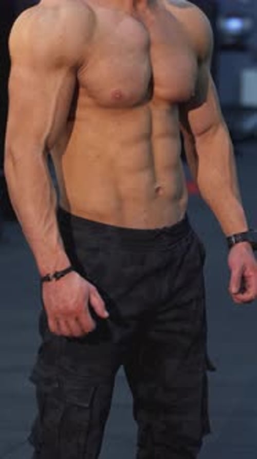 Portrait muscular male bodybuilder with naked body. Handsome sportsman posing on camera in the gym.