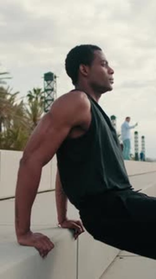 Vertical video, Man Doing Bench Tricep Dips Exercise by the Beach