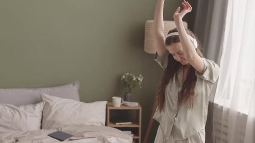 Young Woman in Headphones Dancing to Music at Home