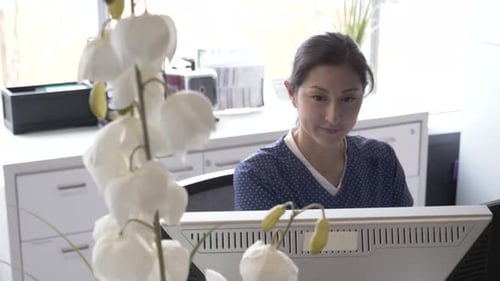 Nurse uses computer at hospital reception for healthcare administration