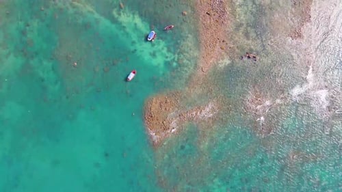 Aerial view of small tourist boats moving slowly over turquoise blue sea water. Gentle waves breakin