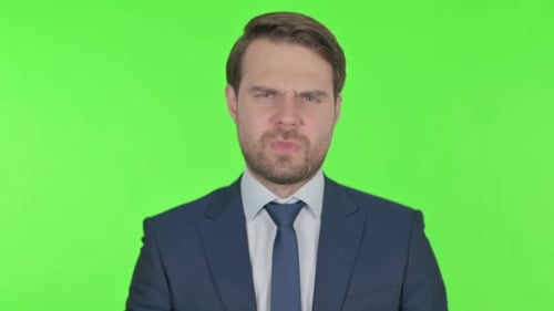 Thumbs Down by Young Businessman on Green Background
