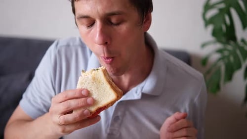 Man Enjoys a Sandwich for Lunch Indoors