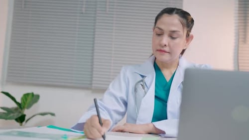 Female doctor writes data from laptop in notebook while sitting in office at table in clinic Therapi