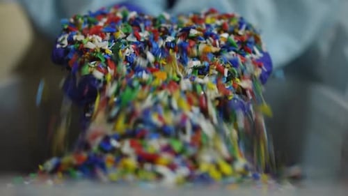 Closeup Shredded Multicolored Plastic Garbage with Female Hands in Gloves Raising Smashed Trash