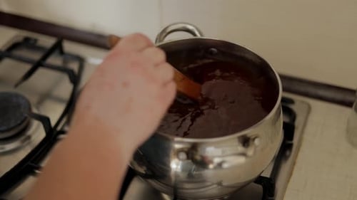 Hands Stirring Sauce in Pot on Stove