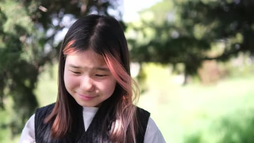 Teen Crying and Wiping Tears in a Garden