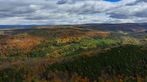Immense rocky landscape wooded by colorful trees. Overcast sky above the scenery of Vermont