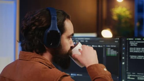 Developer Drinking Coffee and Listening Music While Writing Code