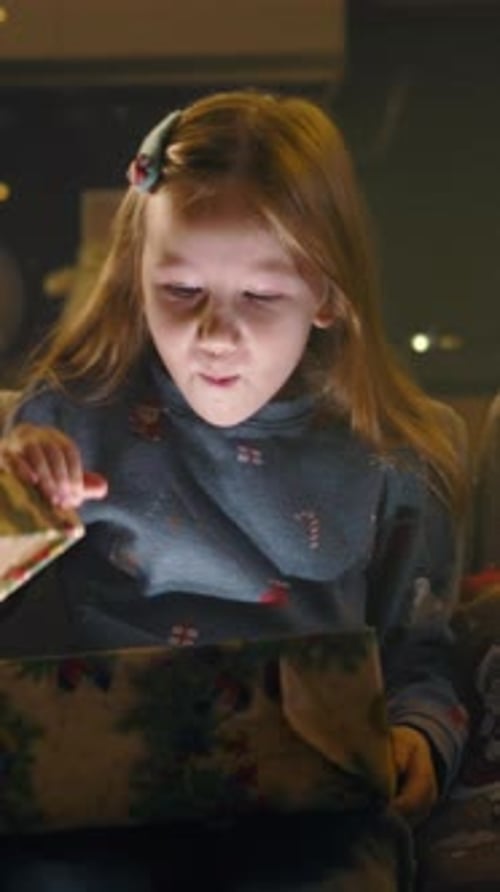 Excited Girl Opens Gift at Christmas Time