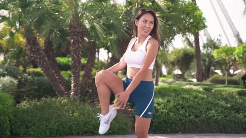 Woman Stretching Leg Muscles in Tropical Park
