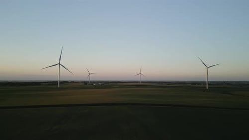 Aerial Wide View Footage of a Wind Park with Wind Turbines Standing in a Wheat Field at Sunset
