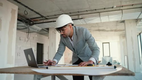 Architect Working on Building Plans in Unfinished Building