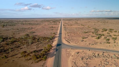 Aerial view above 90 miles straight road, australia on a sunny, desert outback, tilt , drone shot