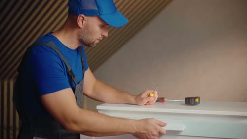 Man Installs Cabinets While Measuring and Assembling Furniture in a Bright Modern Kitchen Space