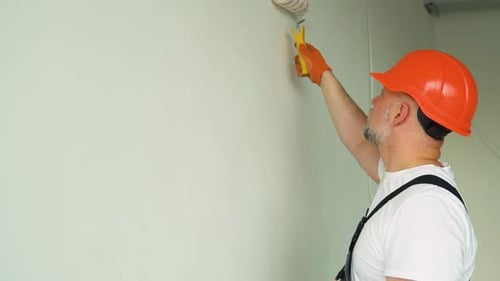 Man Painting Wall with Roller Inside Building